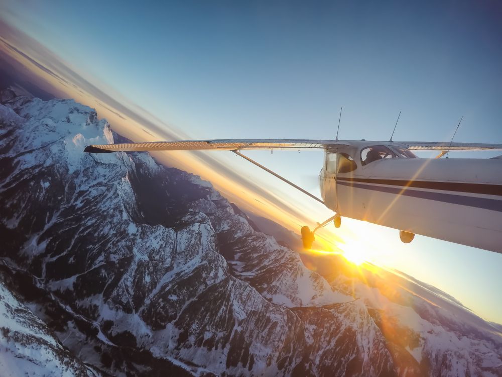 the small plane flying over snow capped mountains demonstrating roll pitch and yaw 