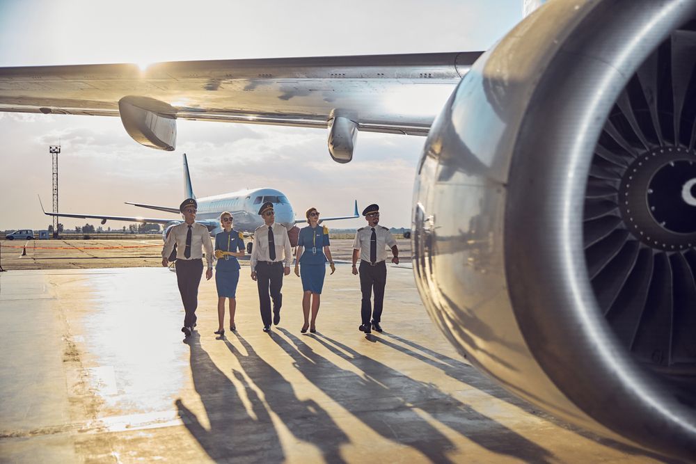 Pilots walking on a tarmac next to a plane engine.