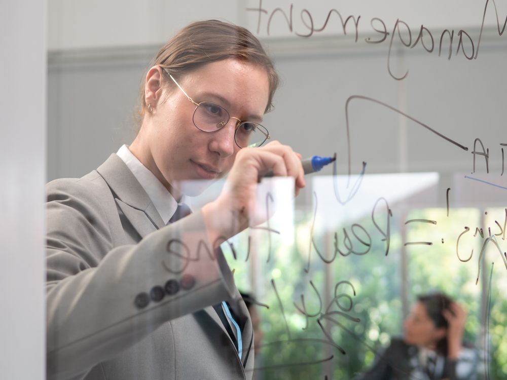 young female flight instructor writing on whiteboard in a classroom as part of Part 141 Flight School procedures