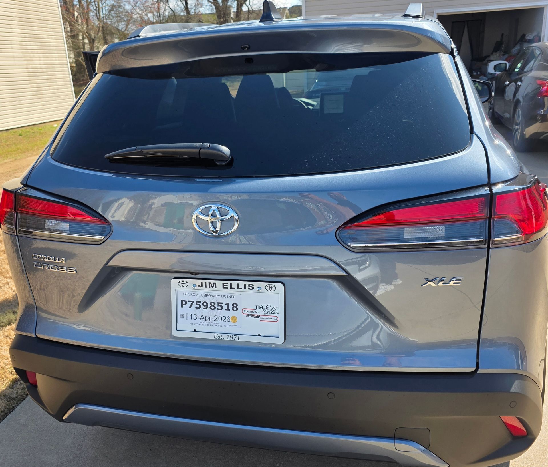 Silver Toyota Corolla, front view, parked on driveway next to a dark blue car, sunny outdoor setting.