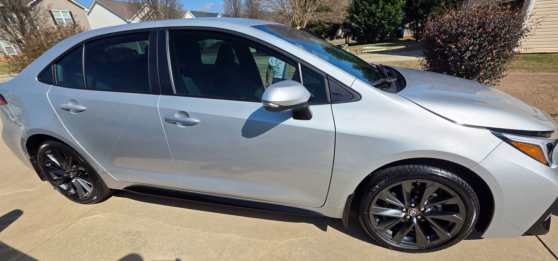 A silver sedan parked on a concrete driveway in a suburban residential setting.