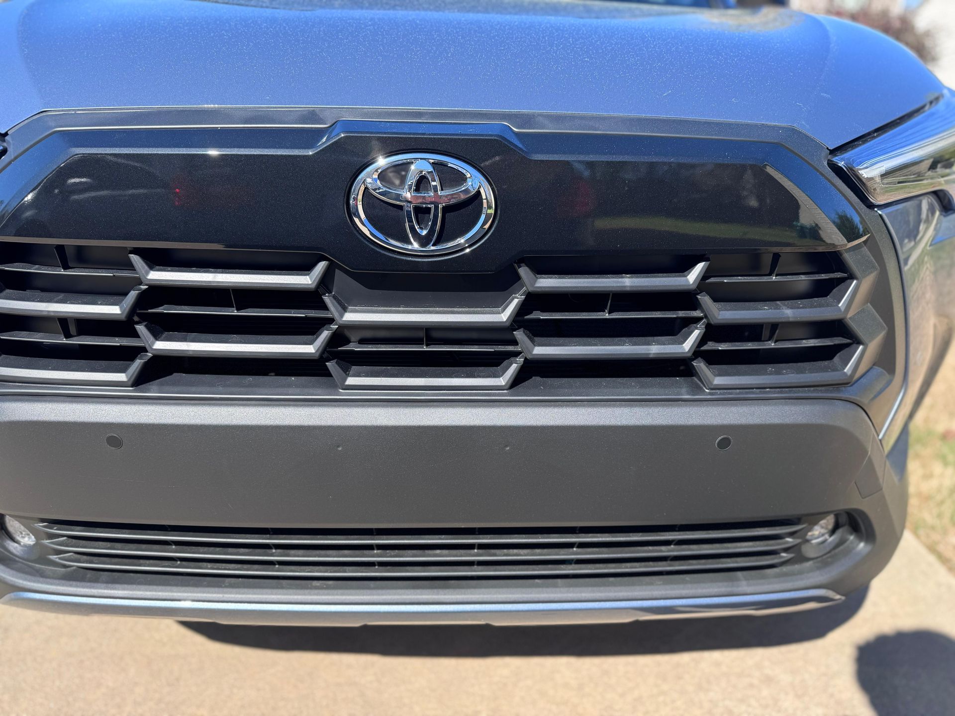 Close-up of a blue Toyota vehicle's front grille, featuring the chrome emblem and black honeycomb mesh design.