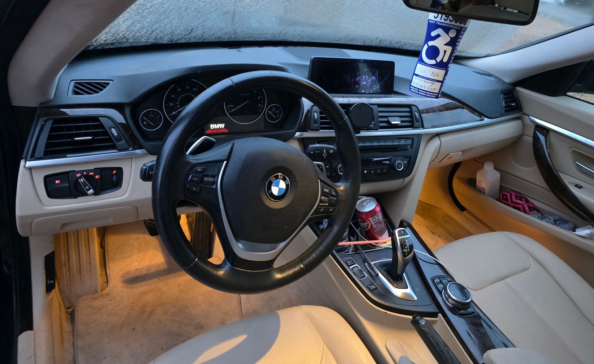 The interior of a BMW with tan leather seats, a black dashboard, a steering wheel, and ambient floor lighting.