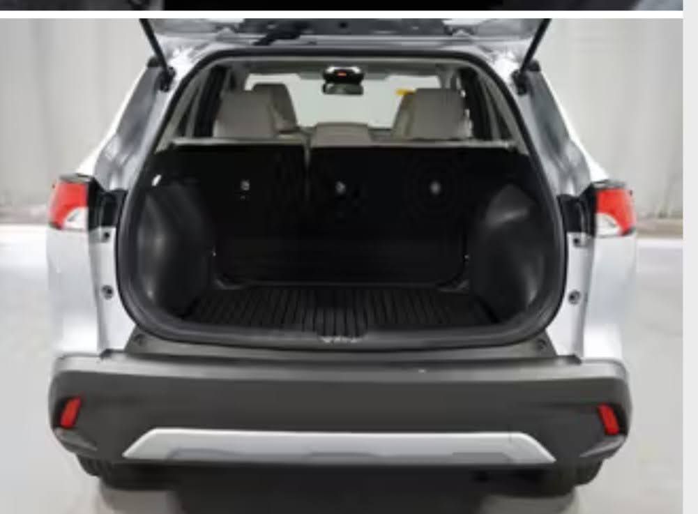 The open trunk of a silver SUV showing a black cargo mat and folded rear seats in a bright, indoor setting.