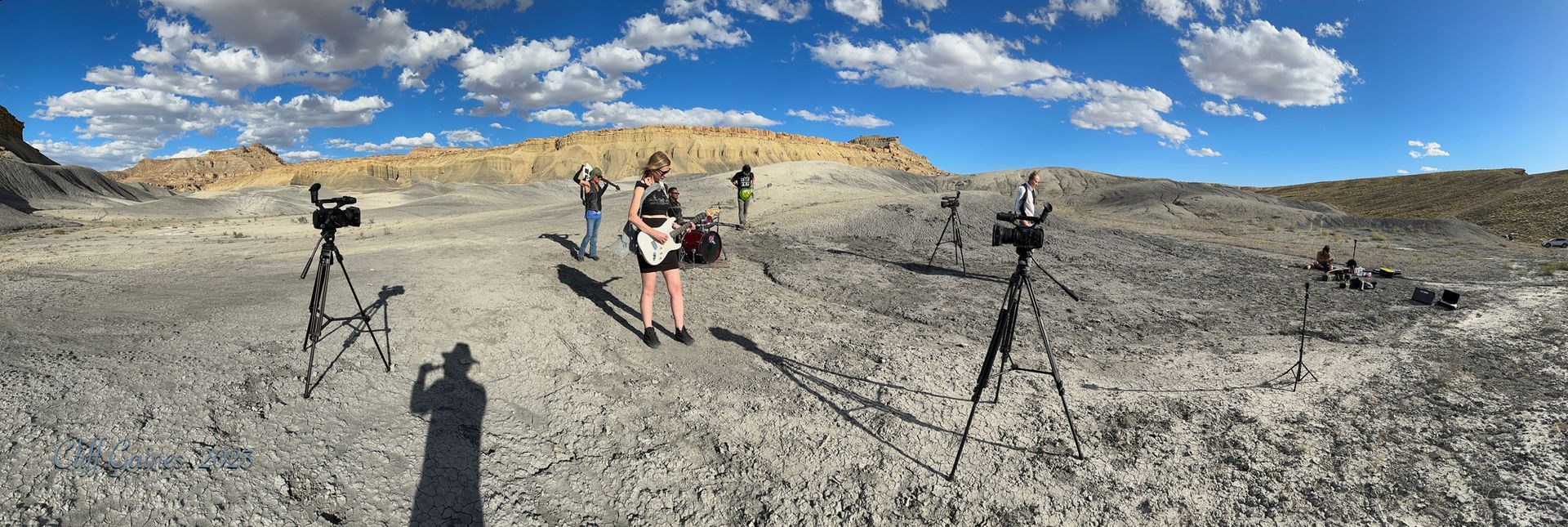 A woman is standing in the middle of a desert holding a guitar.