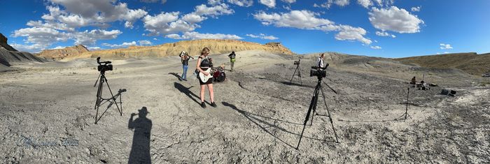 A woman is standing in the middle of a desert holding a guitar.