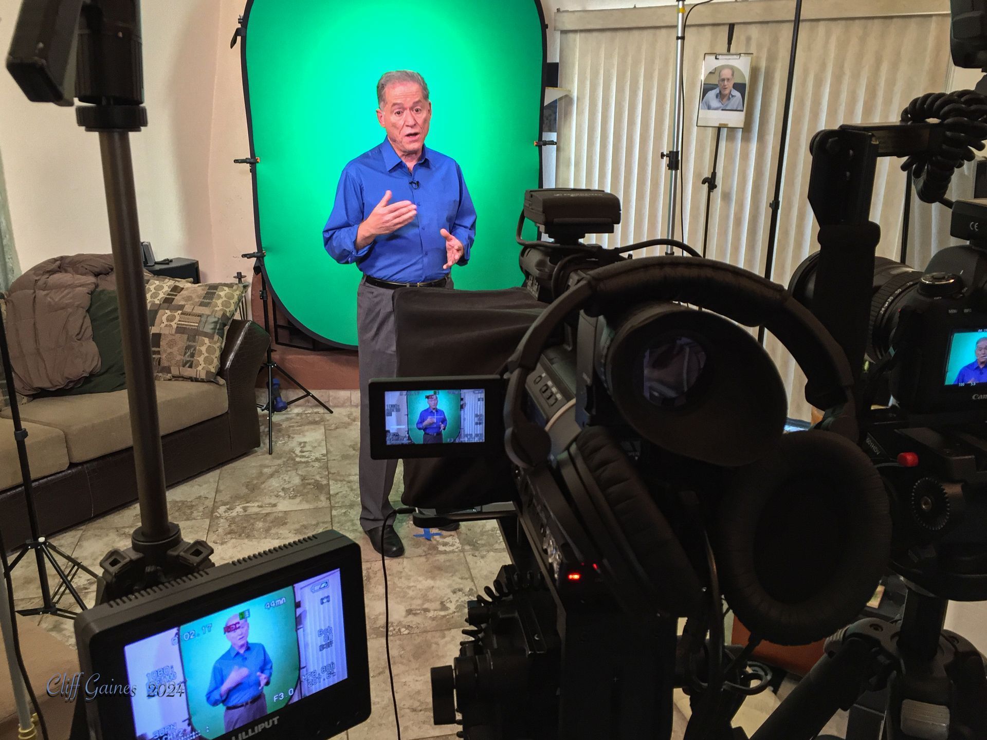 A man is standing in front of a green screen in a living room.