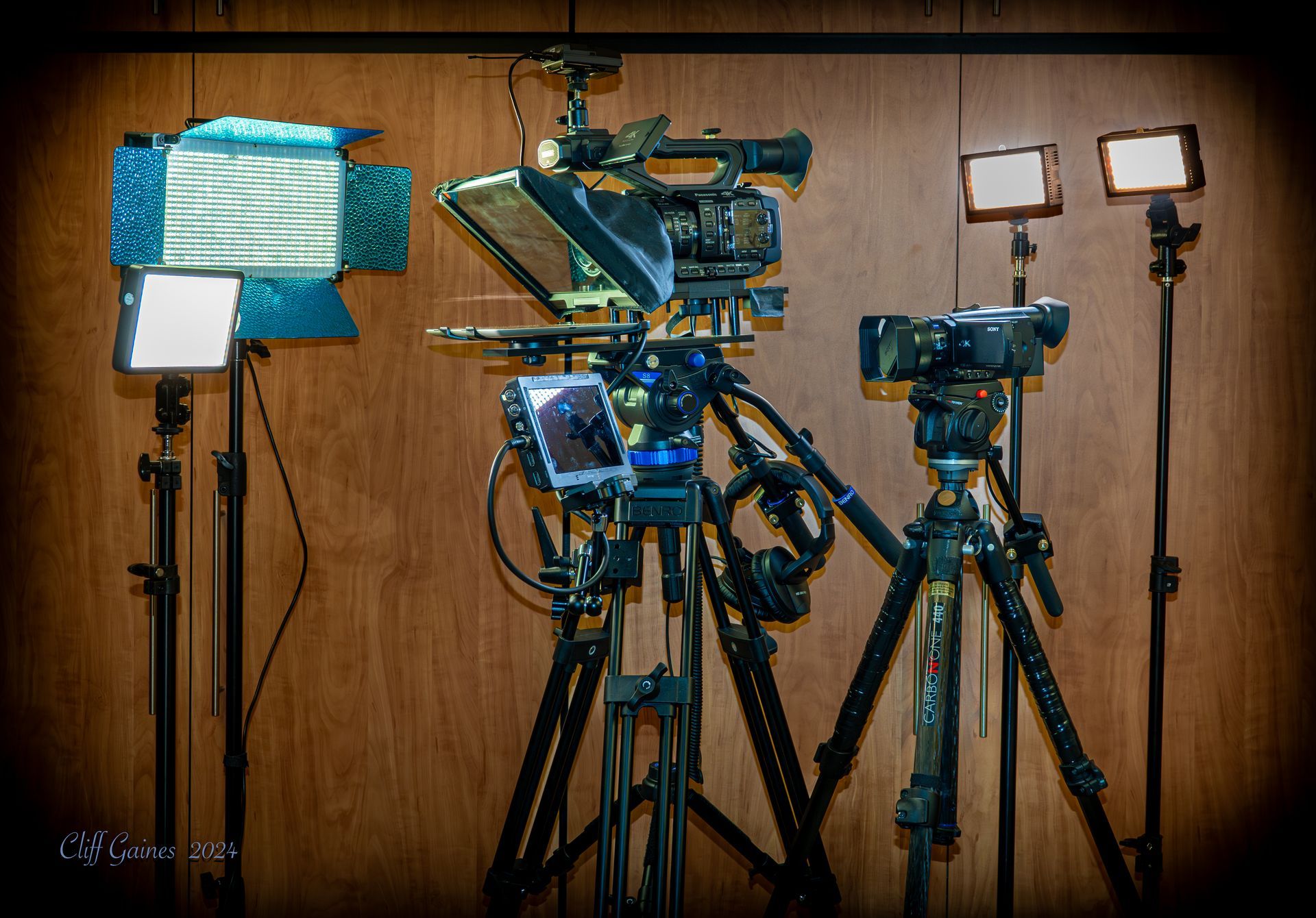 A row of cameras on tripods against a wooden wall