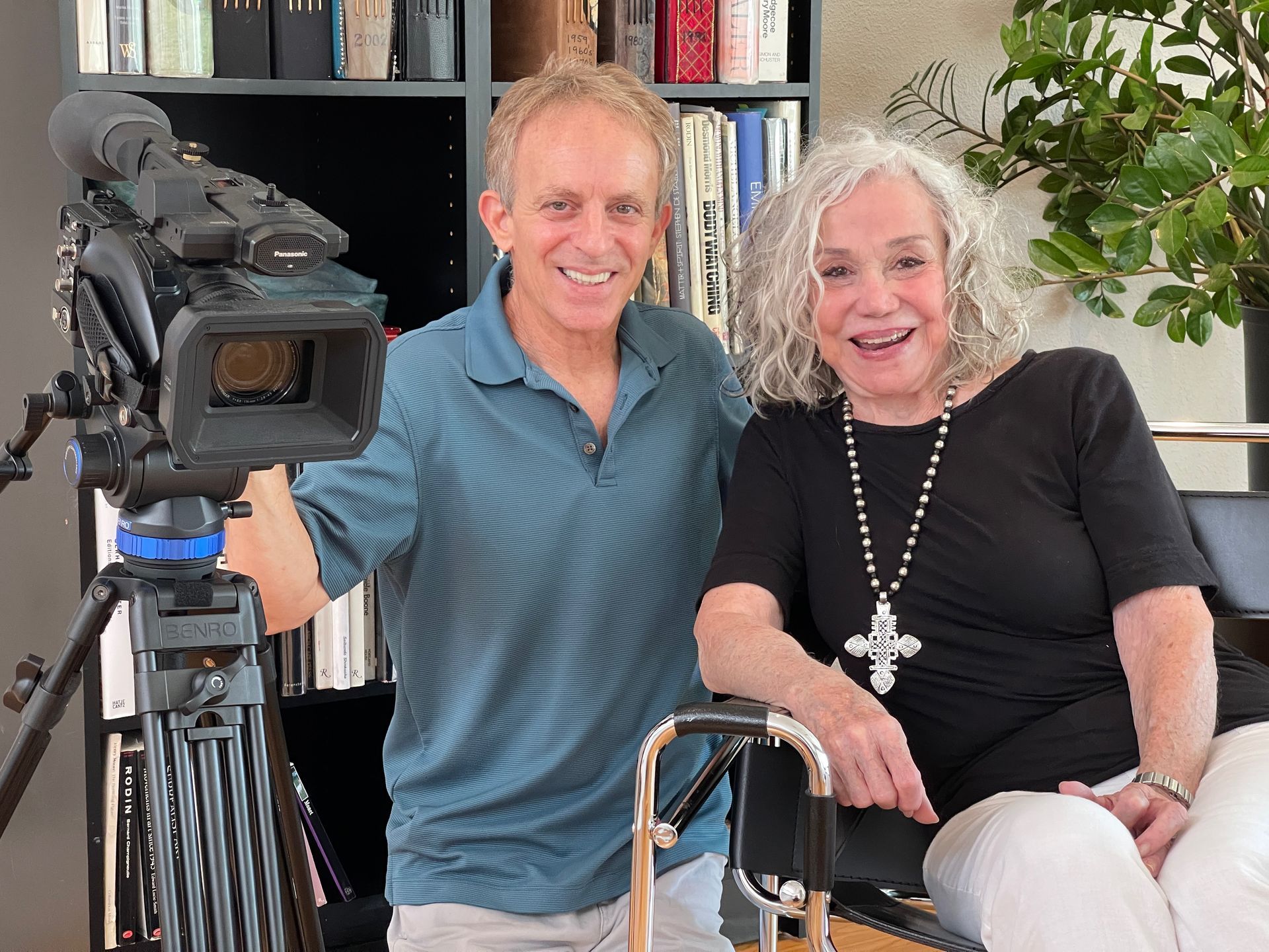 Cliff is holding a camera next to a woman in a chair