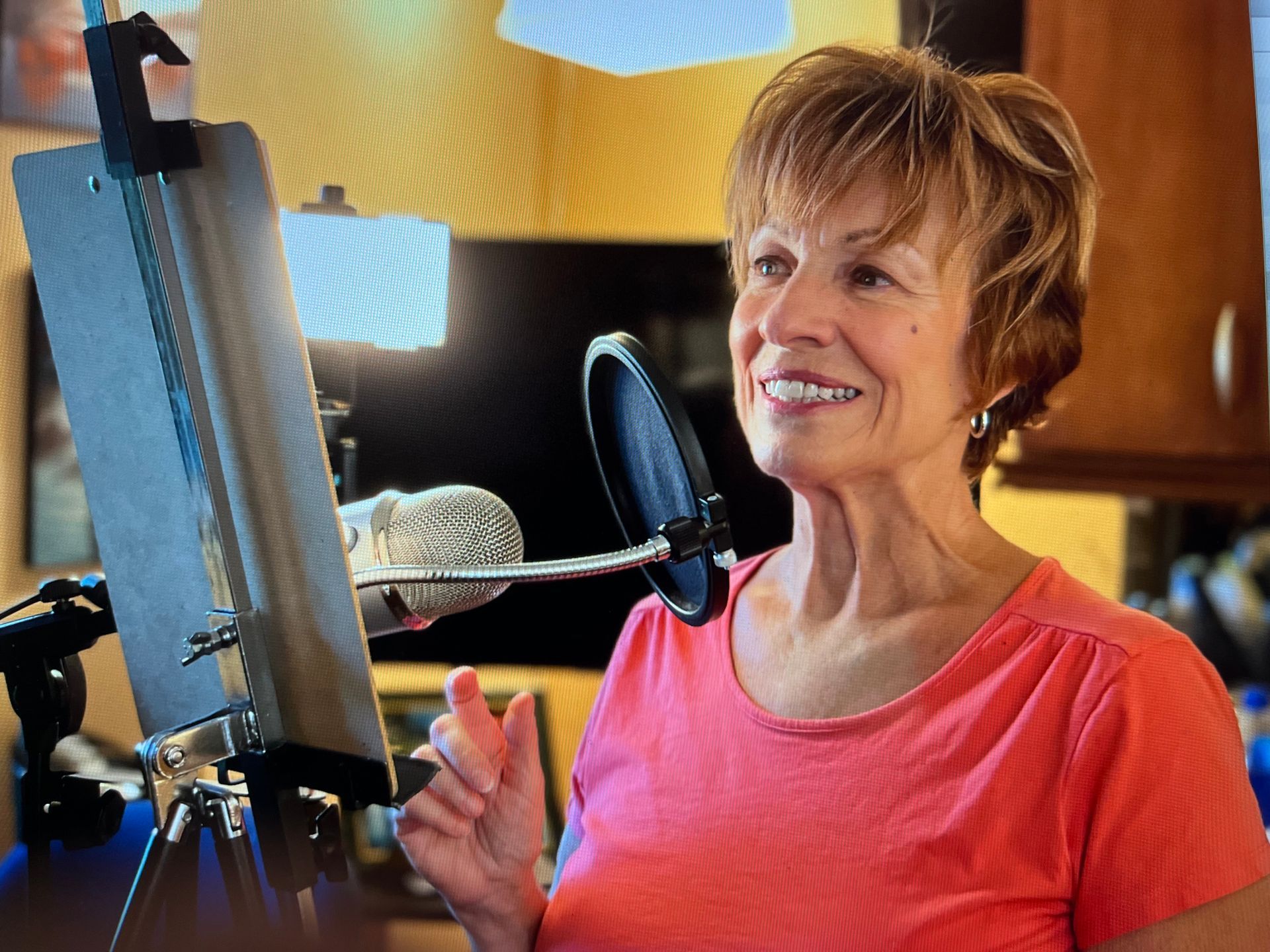 A woman is singing into a microphone in front of an easel.