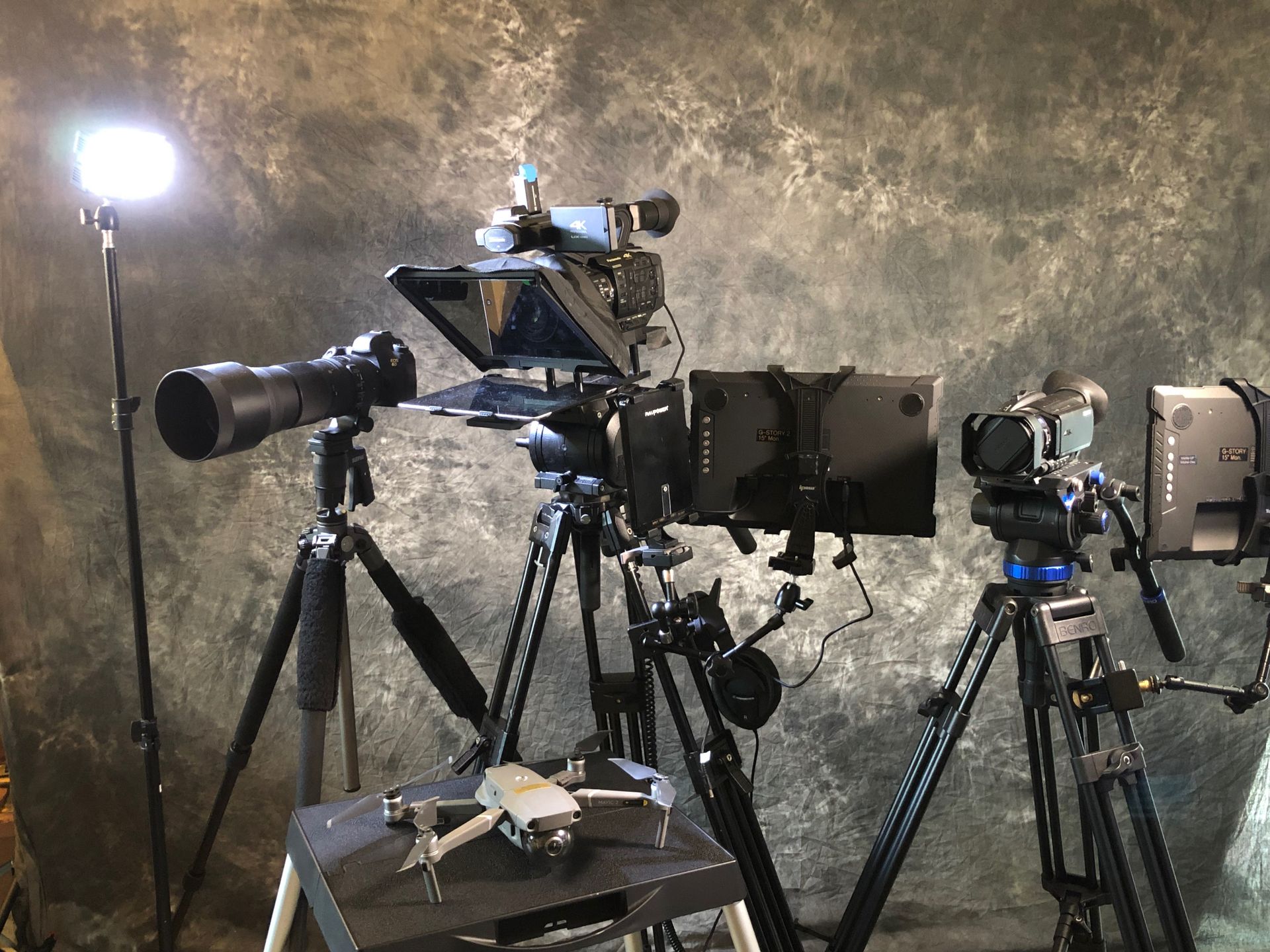 A drone is sitting on a table next to a camera on a tripod.