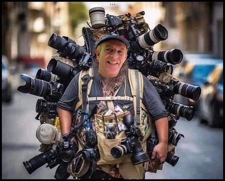 A man is carrying a backpack full of cameras on his back.