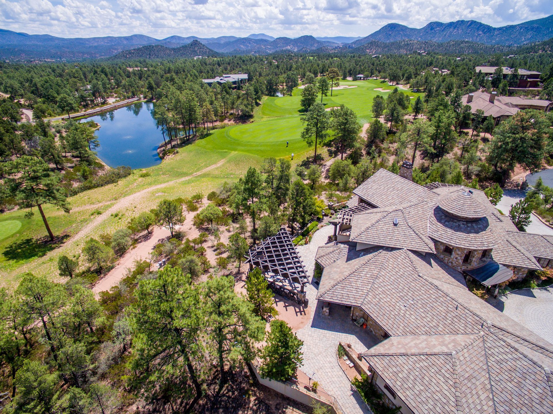 An aerial view of a large house surrounded by trees and a lake.