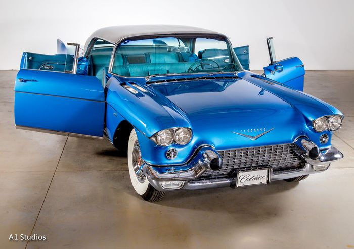 A blue cadillac with its doors open in a garage