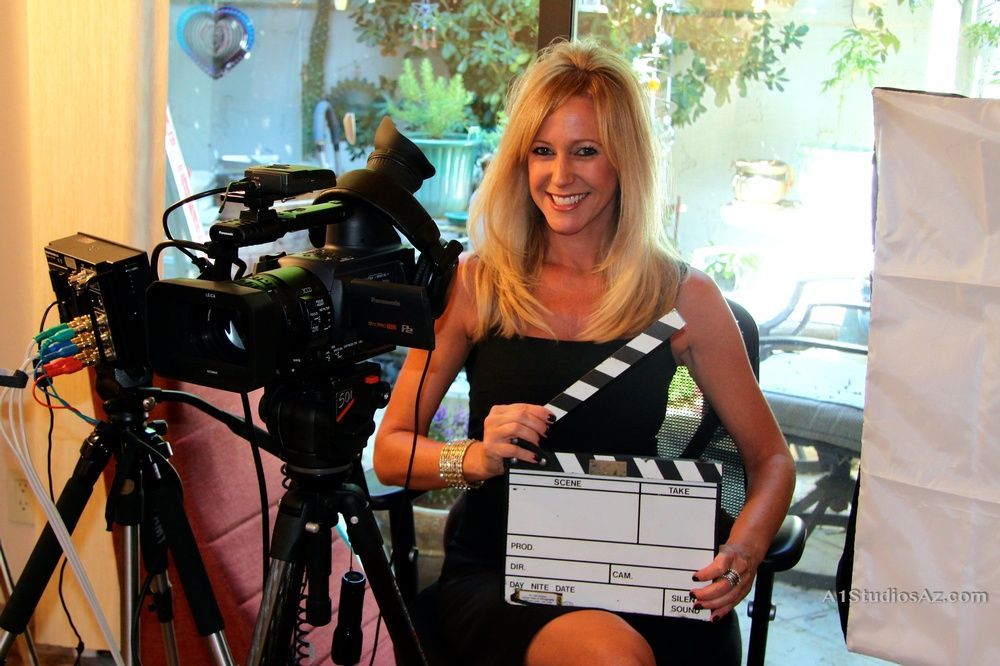 A woman is holding a clapper board in front of a camera