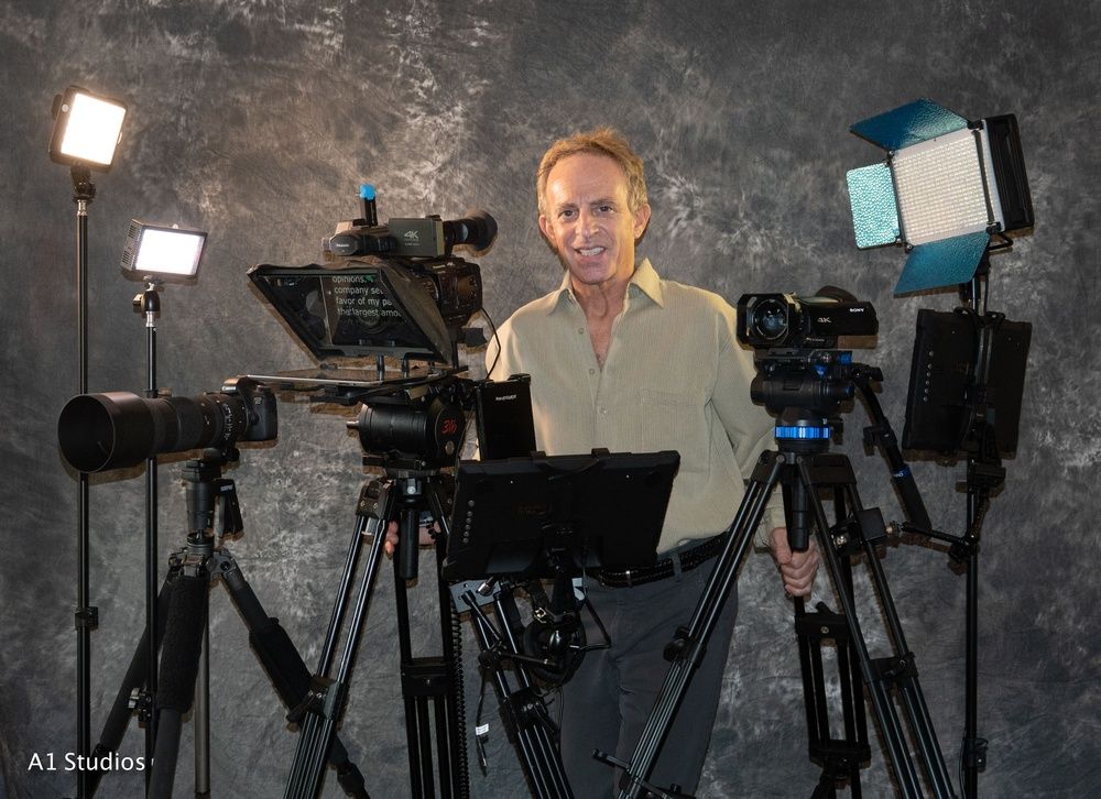 A man is standing in front of a bunch of cameras