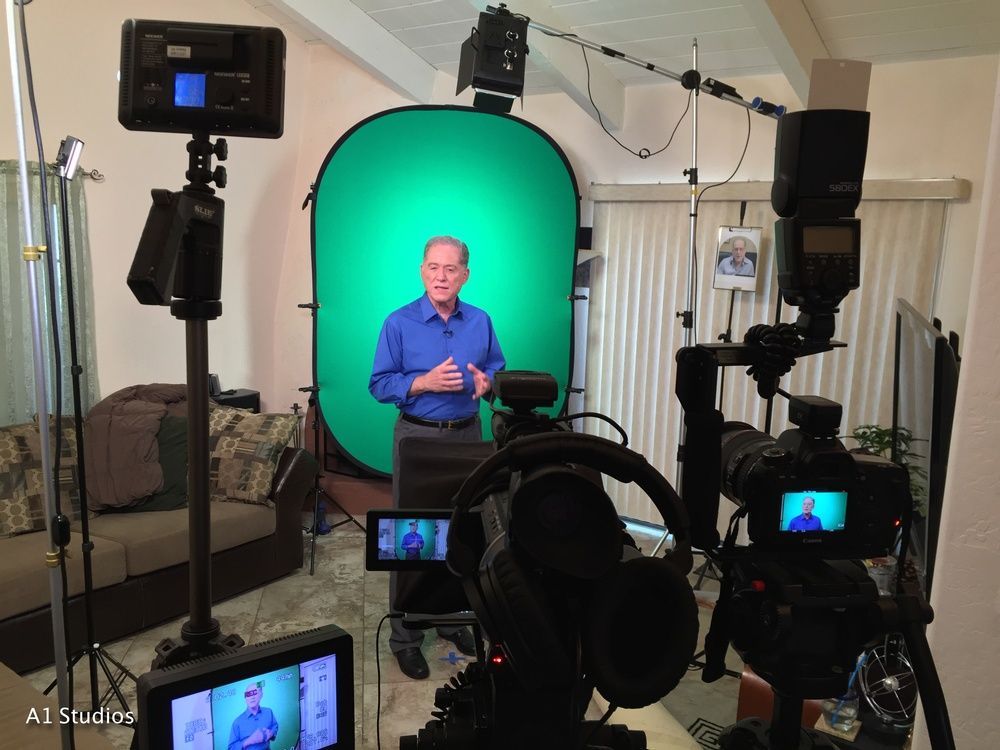 A man is standing in front of a green screen
