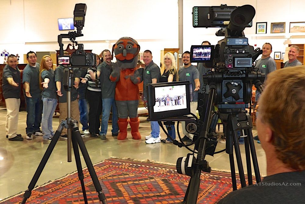 A group of people are standing in front of cameras and a mascot