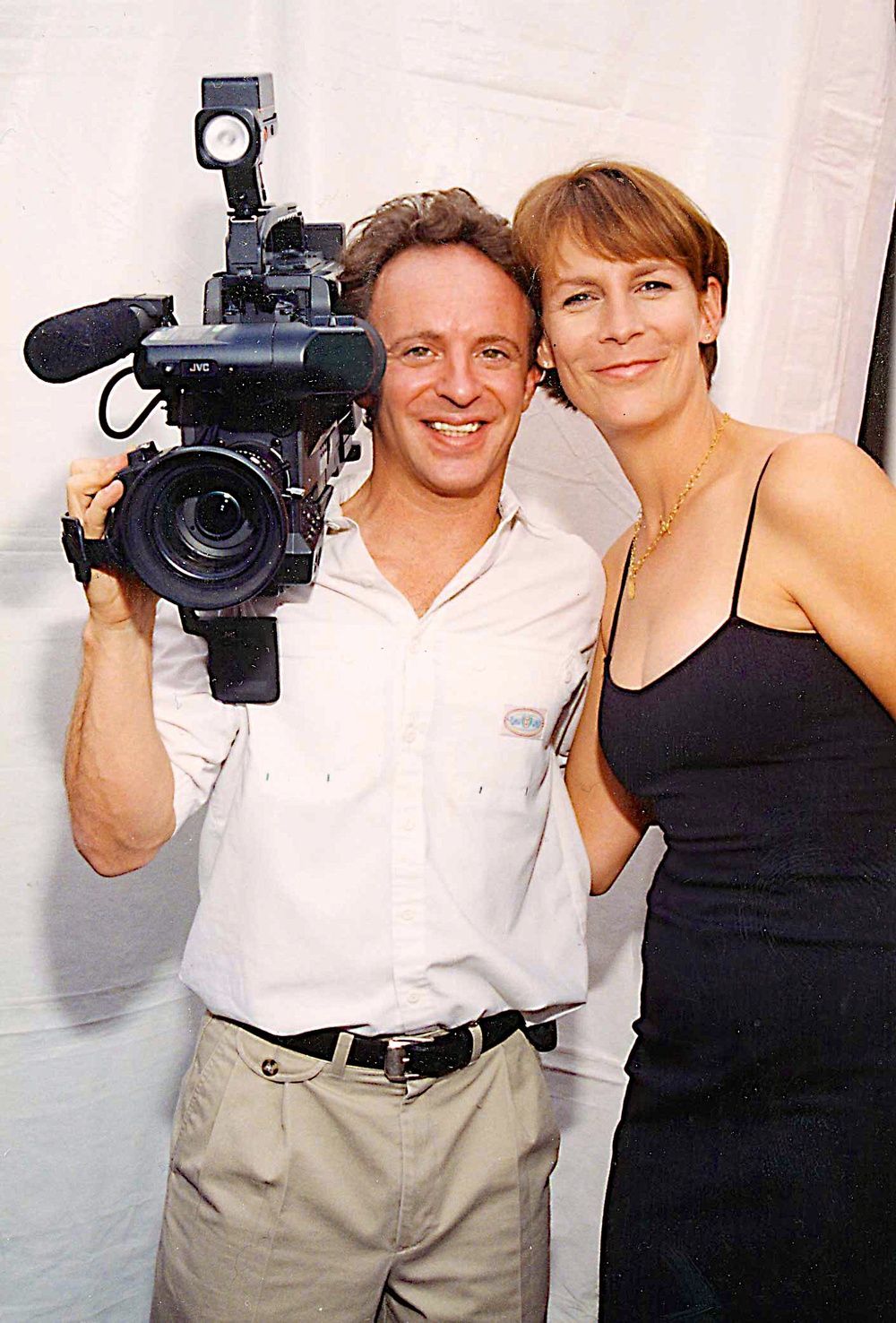A man holding a camera next to a woman in a black dress