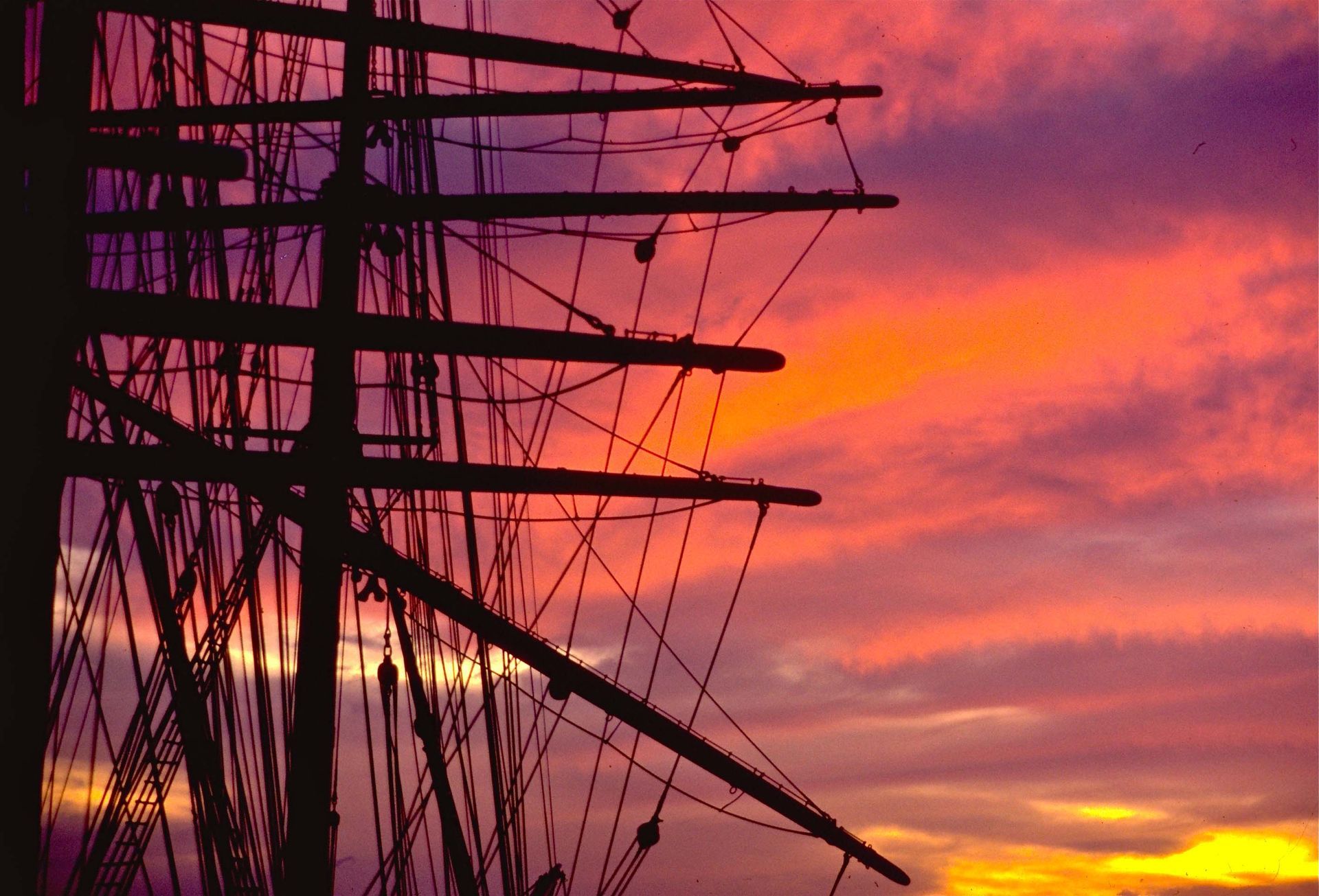 A sailboat is silhouetted against a sunset sky