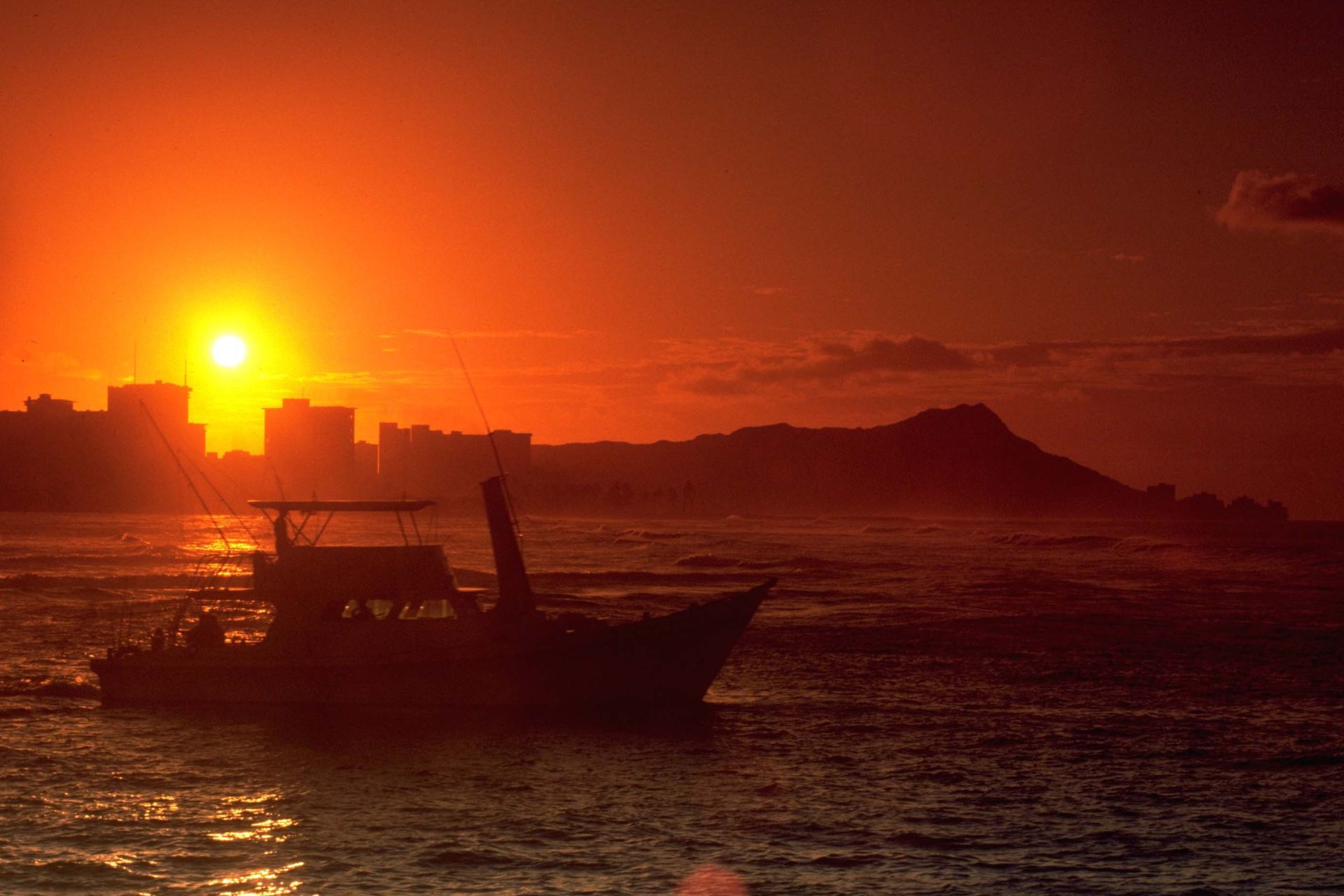 A boat is floating on top of a body of water at sunset.
