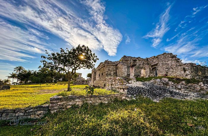 The sun is shining through the clouds over the ruins.