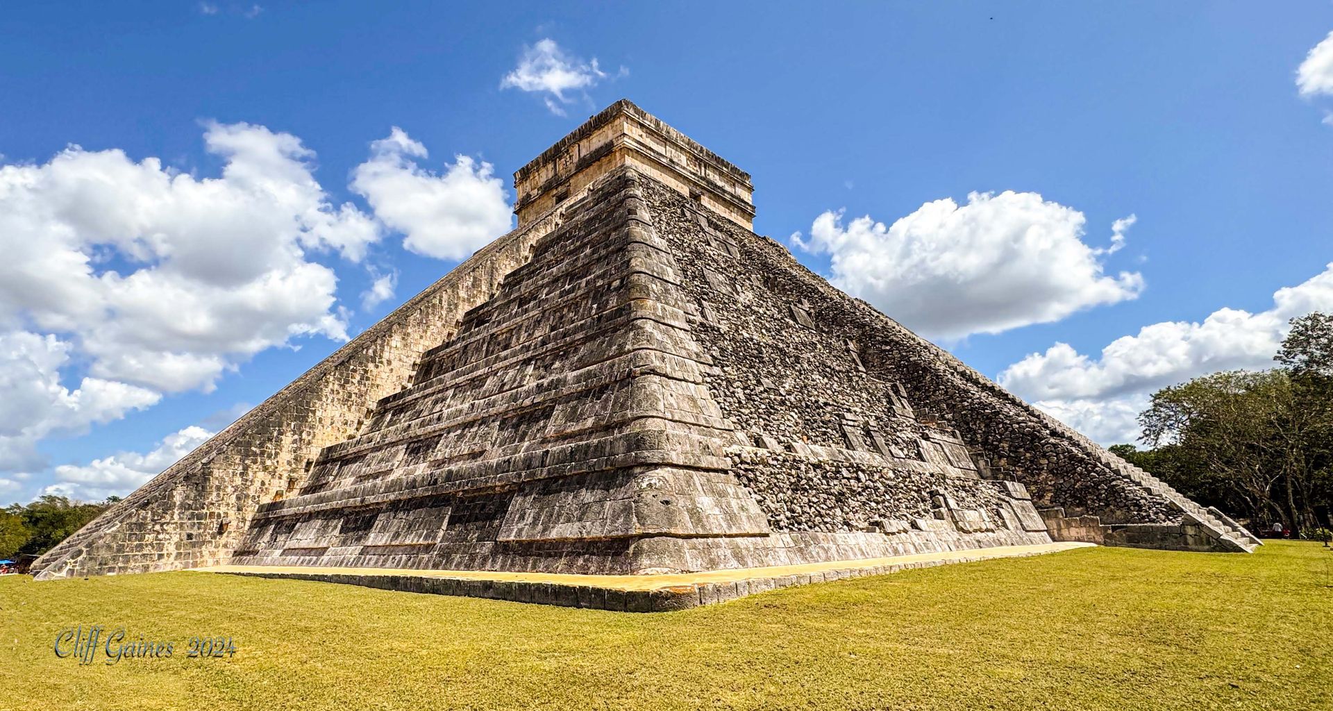 A large stone pyramid is sitting on top of a lush green field.