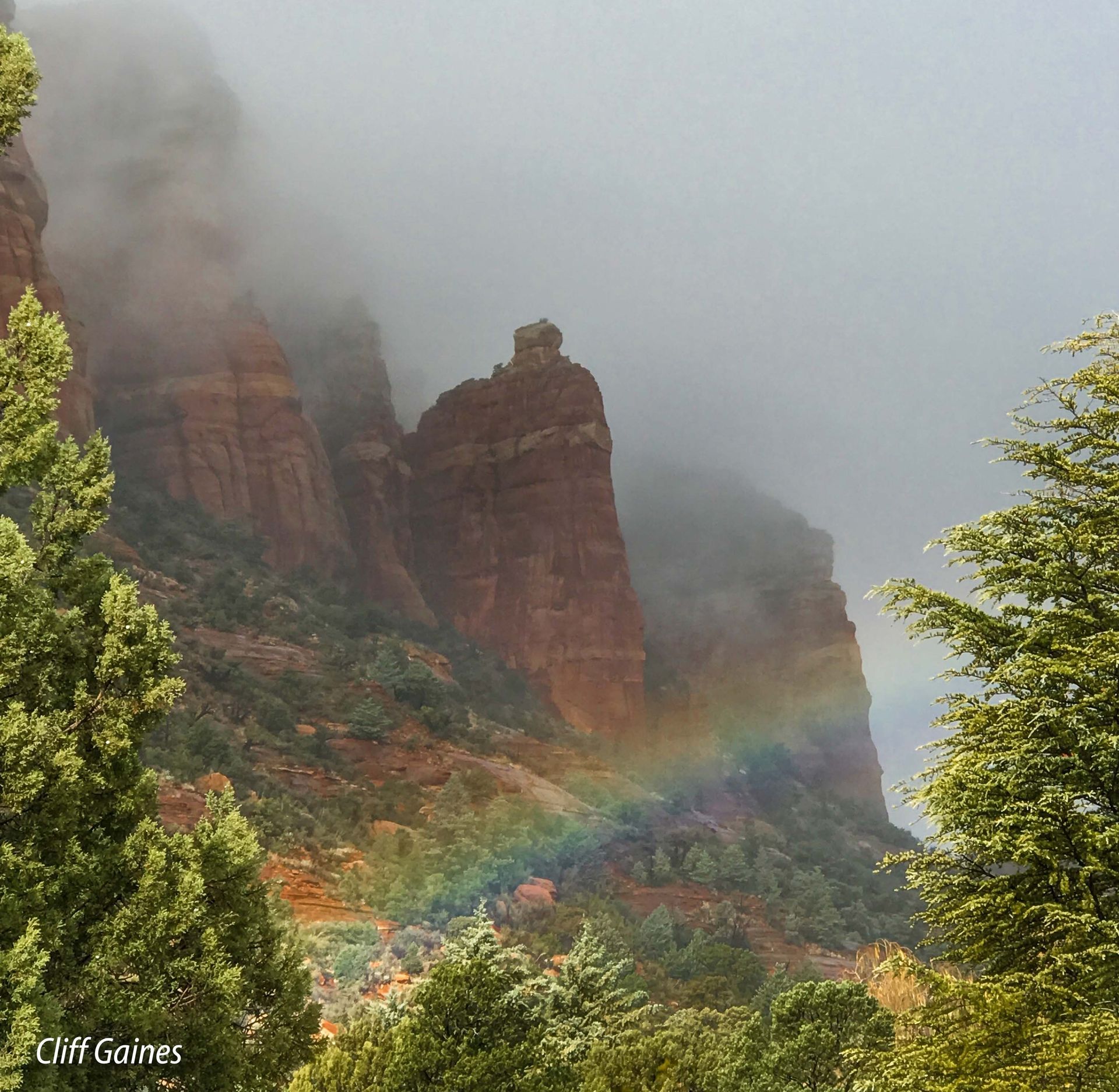 A cliff scene with a rainbow in the distance