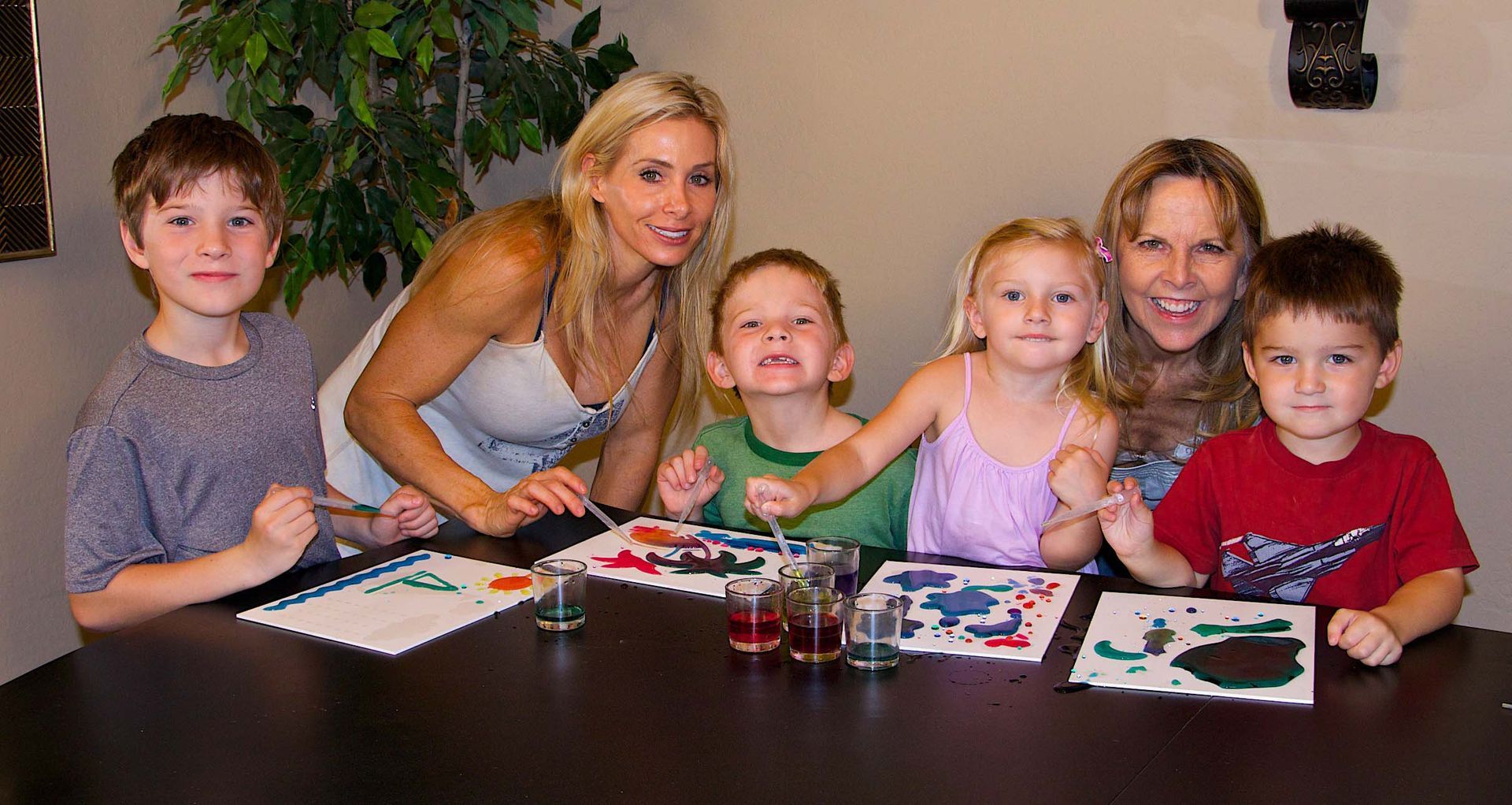 A group of people are sitting around a table painting