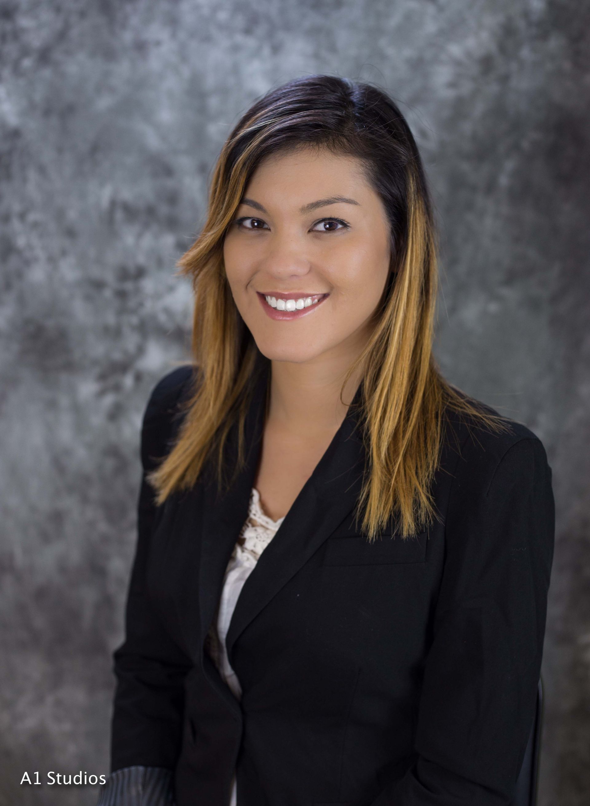 A woman in a black jacket is smiling for the camera.