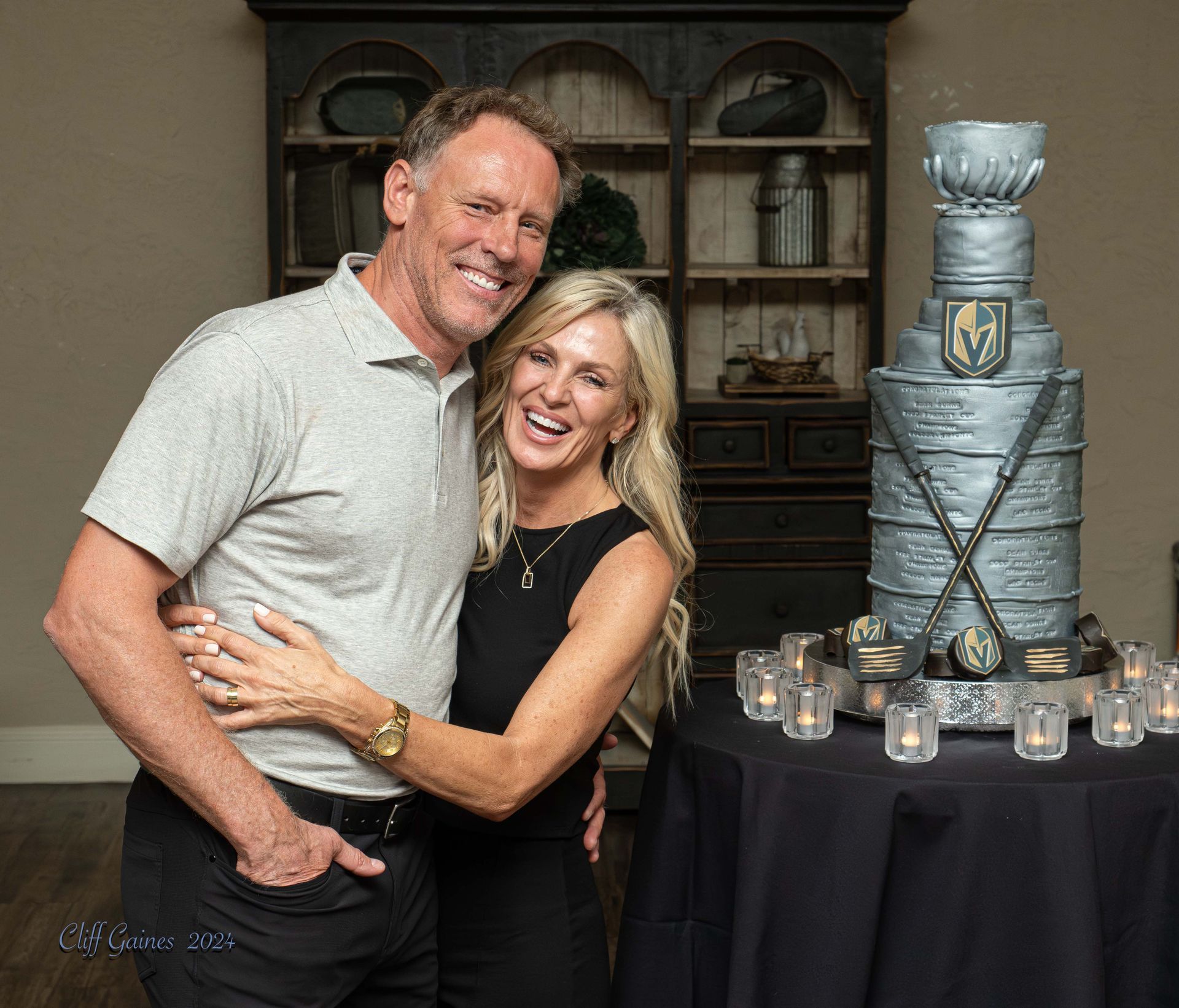 A man and woman are posing for a picture in front of a trophy cake.