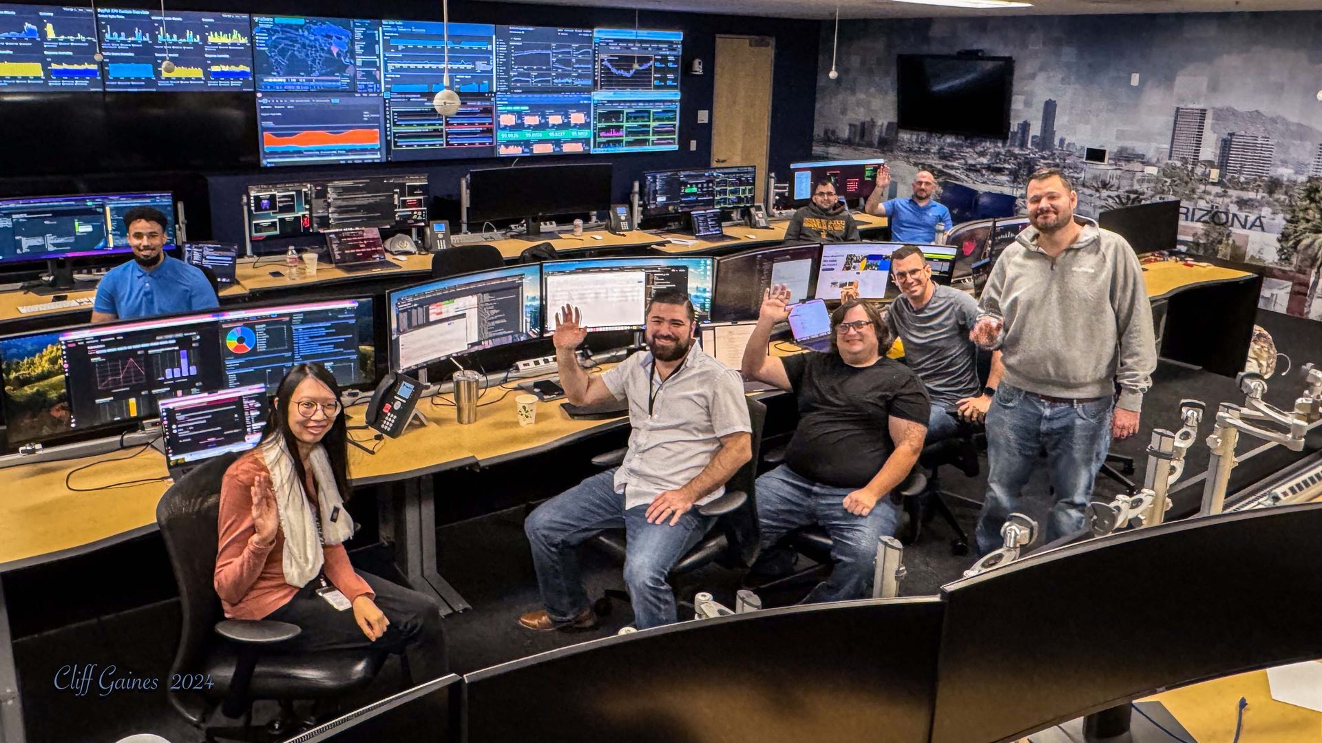 A group of people are posing for a picture in a control room.