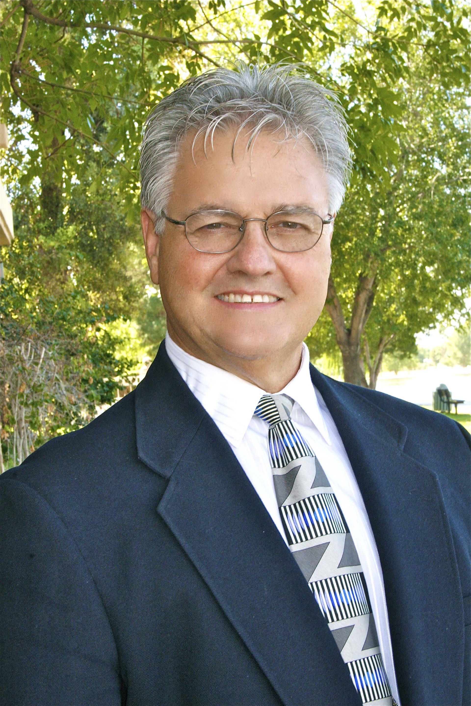 A man in a suit and tie is smiling for the camera