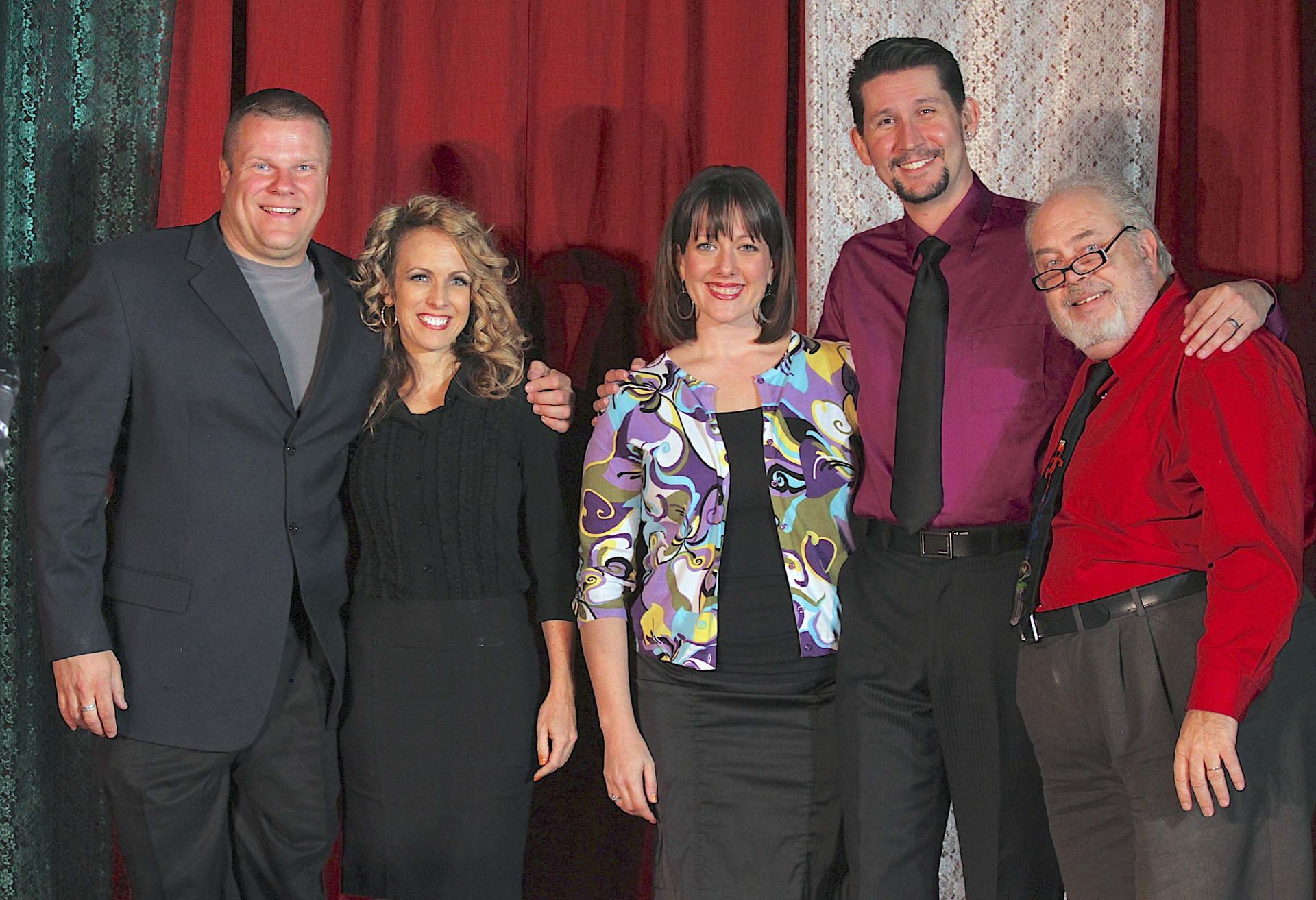 A group of people posing for a picture in front of a red curtain