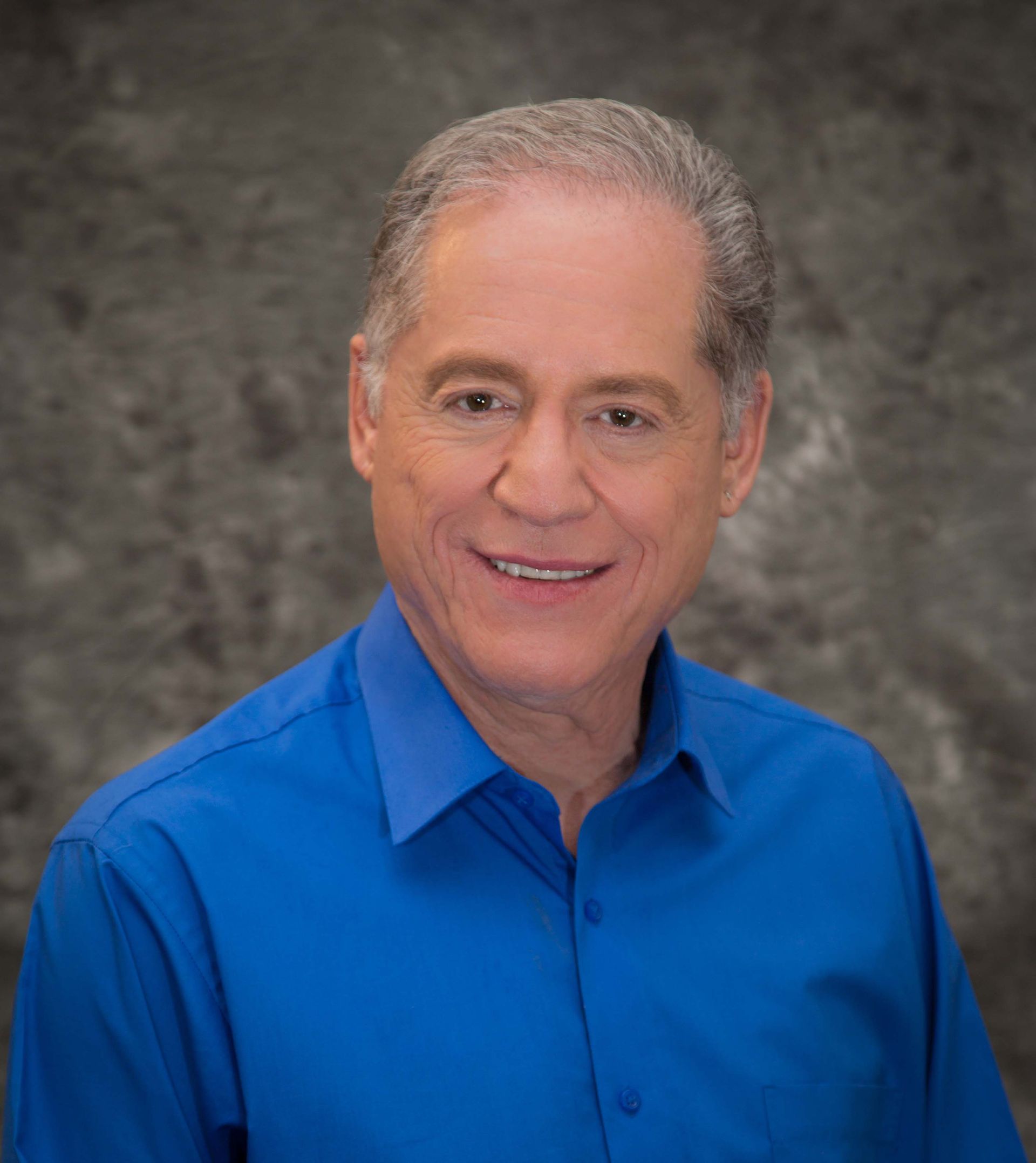 A man in a blue shirt is smiling for the camera.