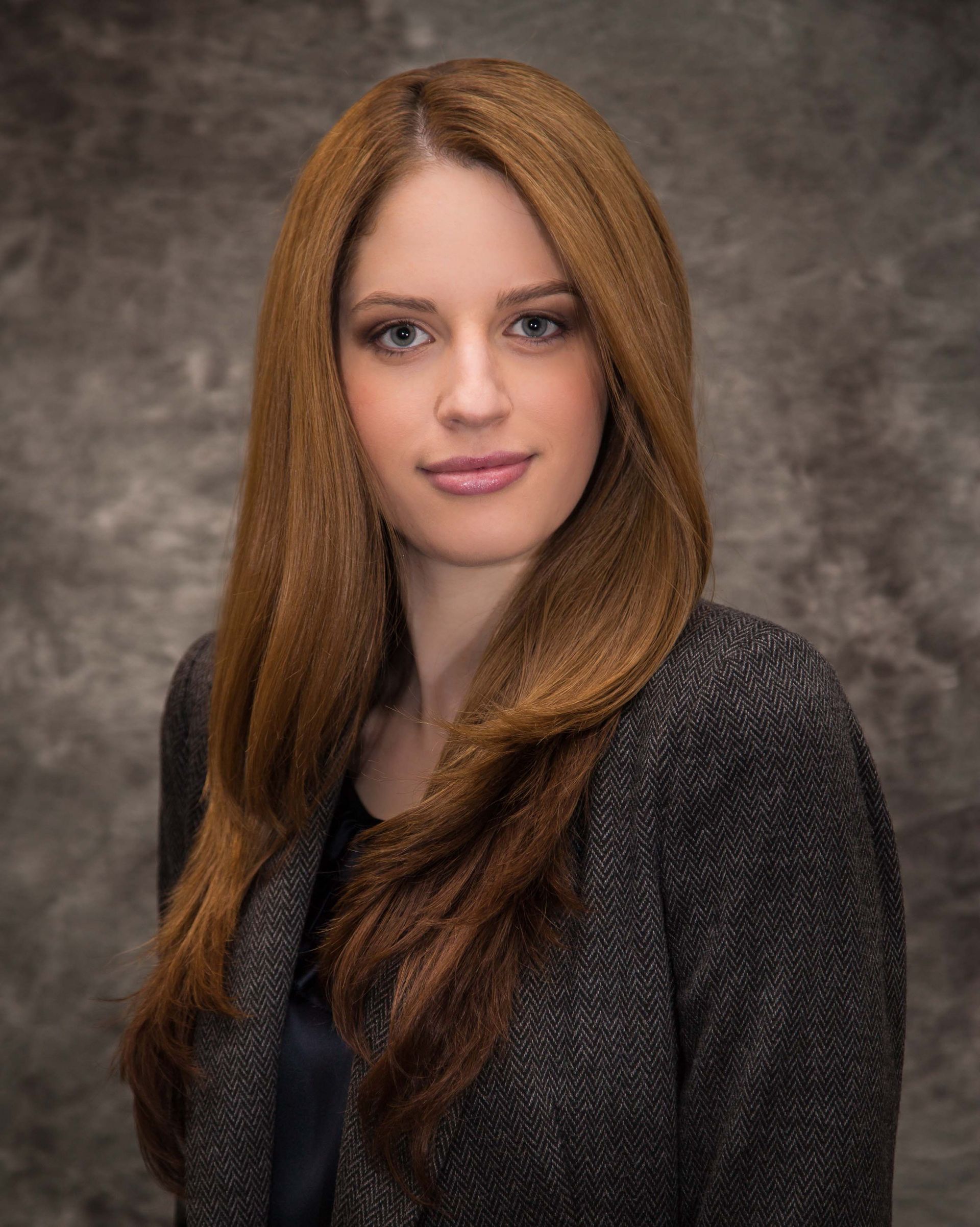 A woman with long brown hair is wearing a gray jacket.
