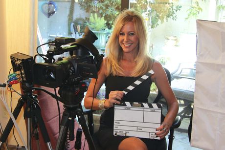 A woman is sitting in front of a camera holding a clapper board