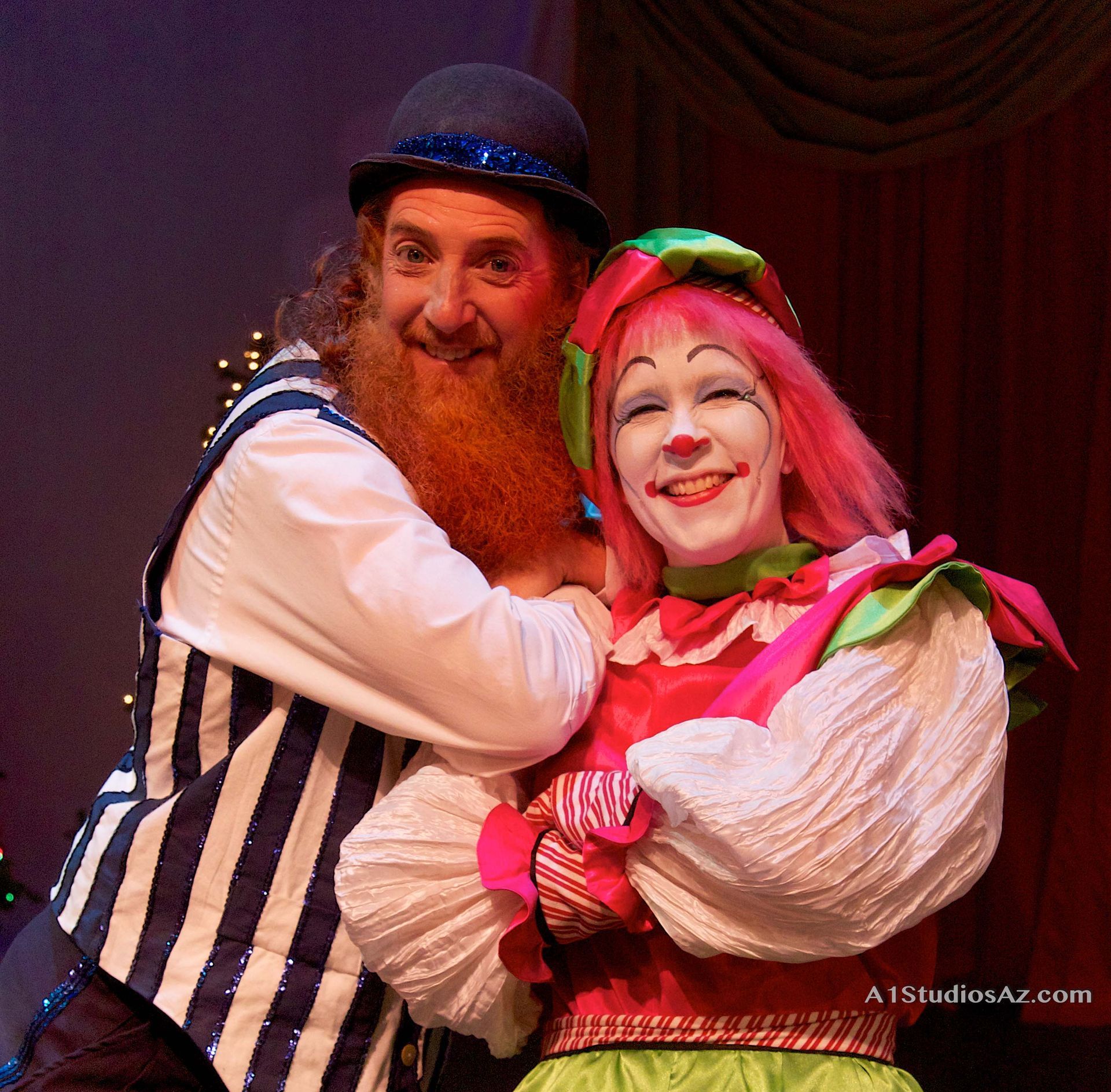 A man with a beard is hugging a clown with pink hair