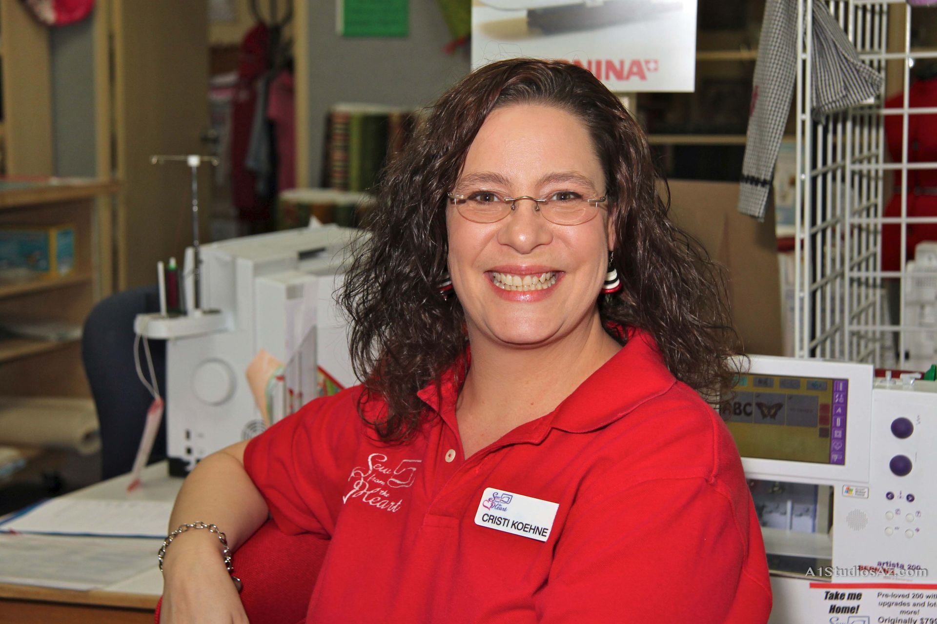 A woman wearing glasses and a red shirt is smiling for the camera