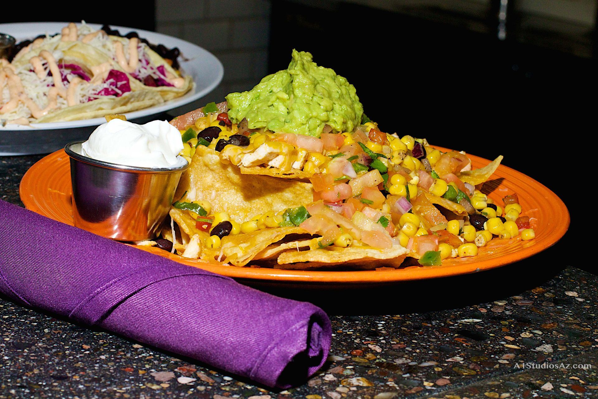 A plate of nachos with guacamole and sour cream on a table.