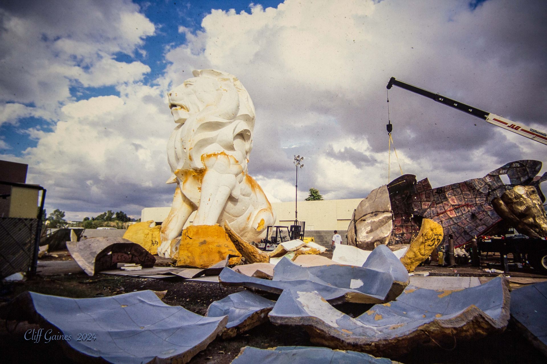 A large statue of a lion is being demolished by a crane