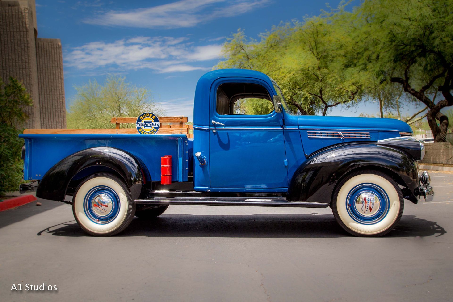 An old blue pickup truck is parked on the side of the road.