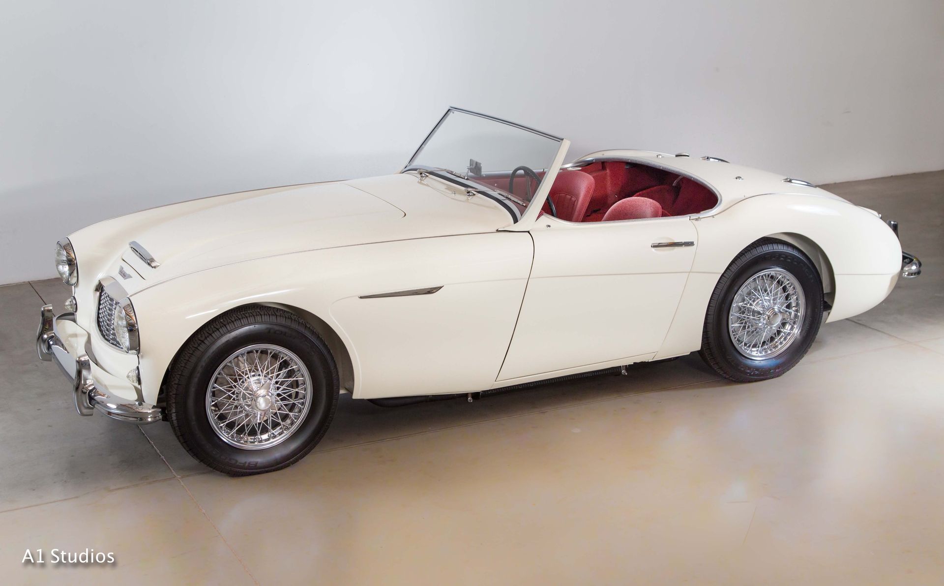 A white sports car with red seats is parked in a garage.