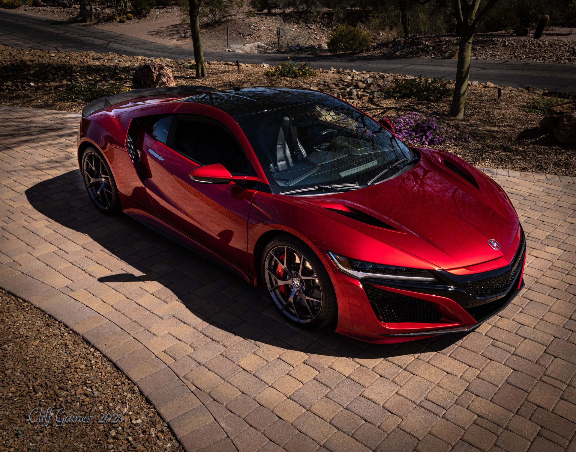 A red sports car is parked on a brick driveway