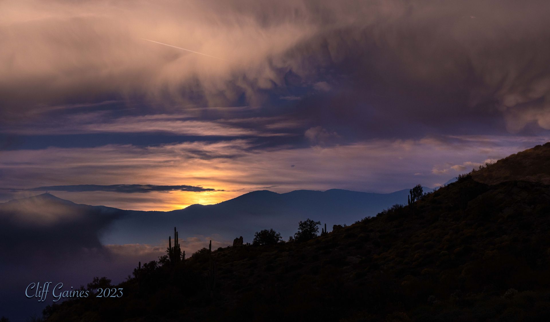 A sunset over a mountain range with a cloudy sky