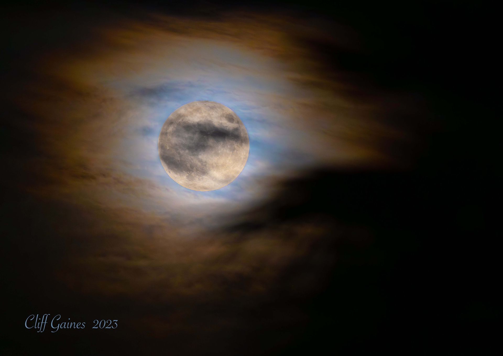 A full moon is visible through the clouds in the night sky.