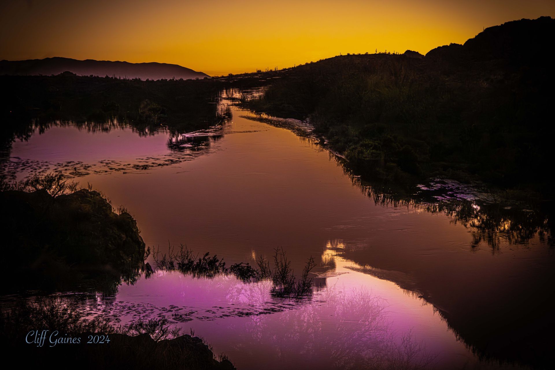 A river with a sunset in the background and purple water