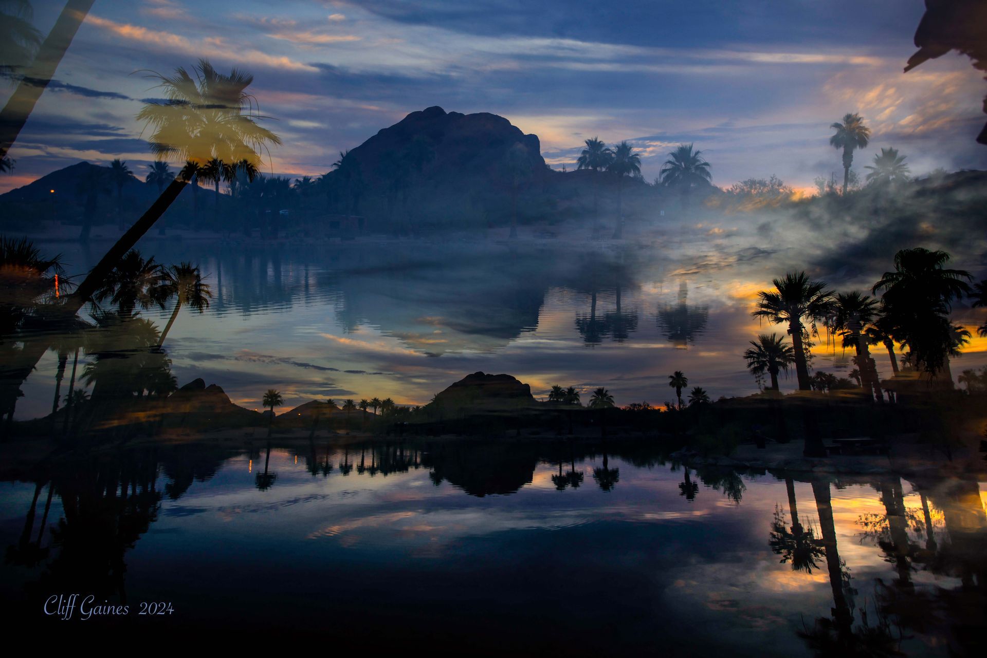 A sunset over a lake with palm trees and mountains in the background
