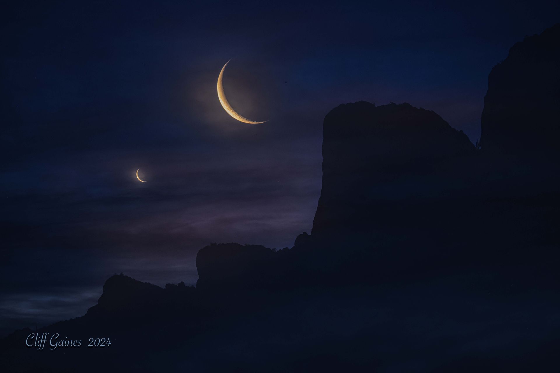 A crescent moon is visible in the night sky above a mountain