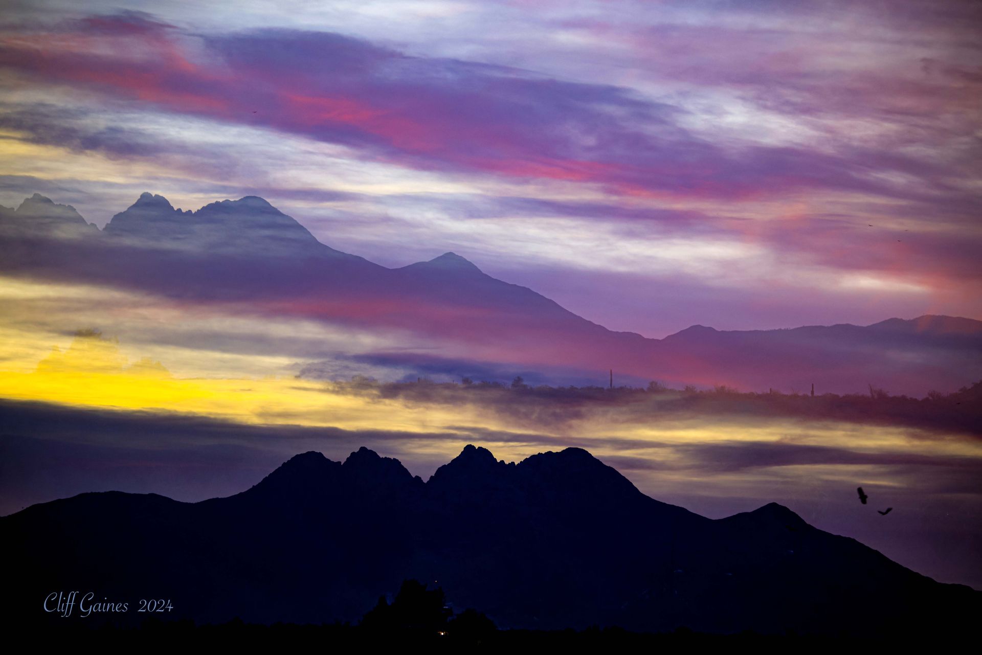 A sunset over a mountain range with purple and yellow clouds